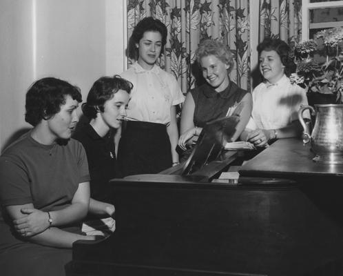 At the Hamilton House--at the piano in the living room, from left to right: Draxie Newson, Bethy Ann Foley, Laurel Hampton, Pat Clarke DeMarcus, and Norma Cable. Received September 25, 1958 from Public Relations