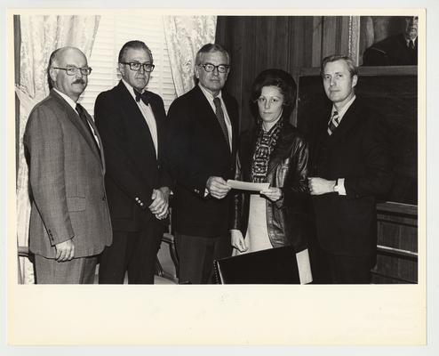 President Singletary (third from left) is standing with four unidentified people and handing something to an unidentified woman