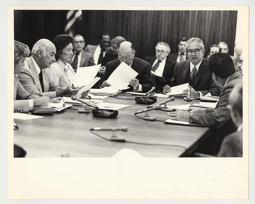President Singletary is (right) seated at a table with unidentified people, reviewing documents and speaking at an unidentified meeting