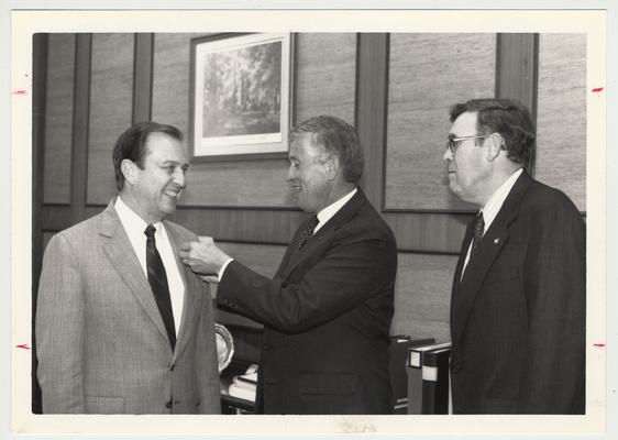 UK Central Development.  John Zachem (center) gives Fellows pin to Charles T. Wethington, Jr. (left) while Lou Swift watches (right).  Communi-K