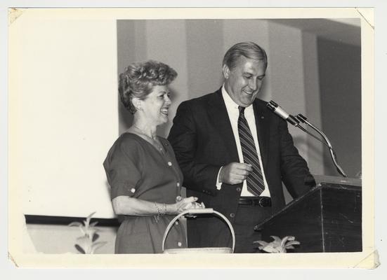 Gloria Singletary stands at a podium with Terry Mobley, head of development and former basketball player (1963 - 1965)