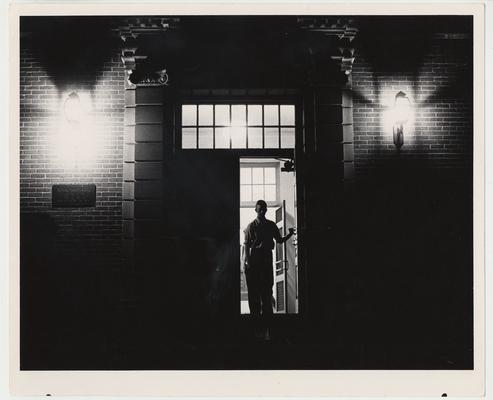 An unidentified man is walking out of the Margaret I. King Library at night