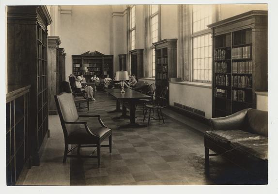 The browsing room in the Margaret I. King Library with bookcases on the walls and people sitting in the chairs reading