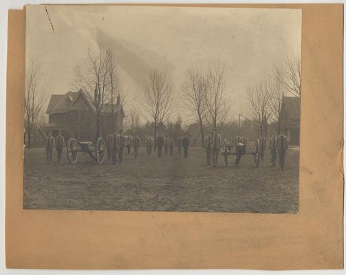Men in uniforms with cannons are in front of J. K. Patterson's house.  Patterson's house was later torn down in order to build the Patterson Office Tower and White Hall Classroom Building