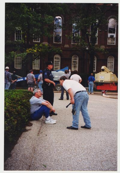 Unidentified men are standing outside of the Administration / Main Building during the fire