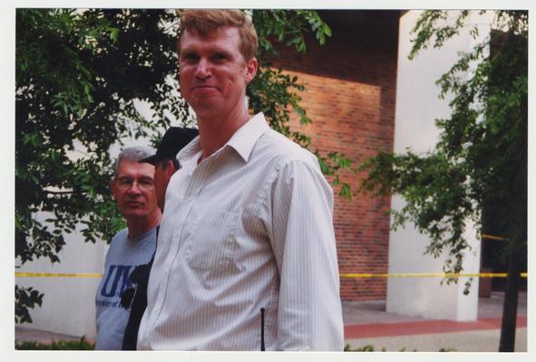 Three unidentified men are standing outside of the Administration / Main Building during the fire