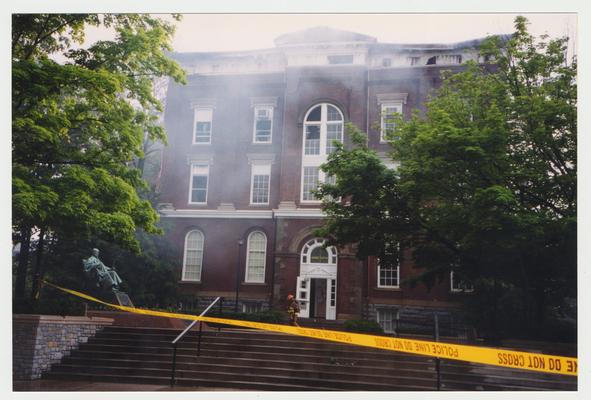 An exterior view of the Administration / Main Building during the fire.  There is an unidentified fire fighter in front of the building