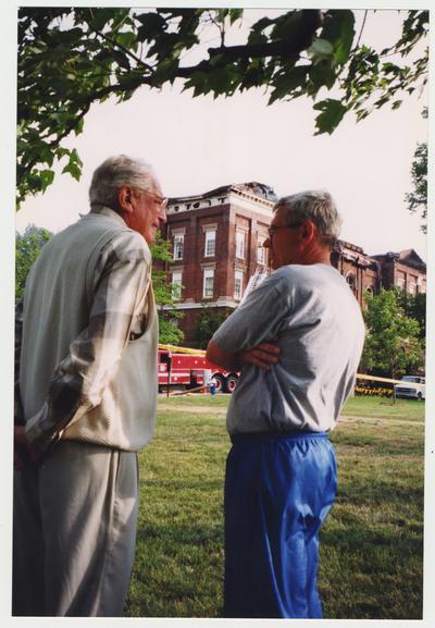 Two unidentified men are standing outside of the Administration / Main Building during the fire