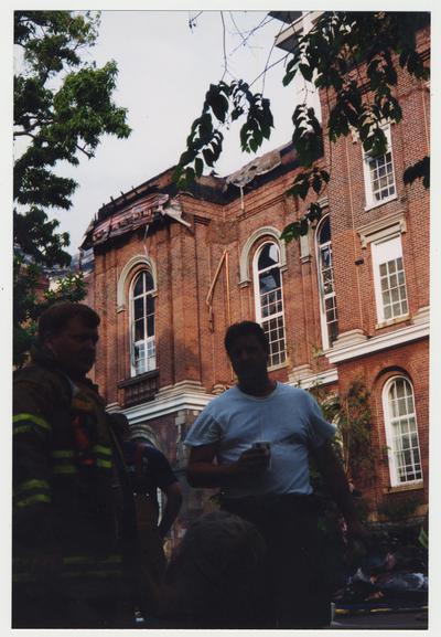 Unidentified fire fighters are standing outside the Administration / Main Building after putting out the fire