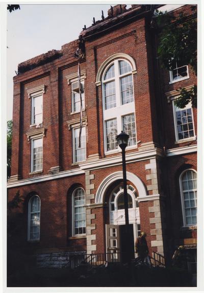 An exterior view of the Administration / Main Building during the fire.  There are two unidentified fire fighters on the steps