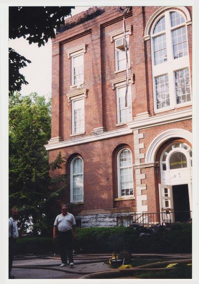 Two unidentified men are standing outside of the Administration / Main Building during the fire