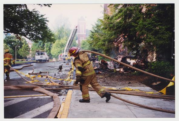 An unidentified fire fighter is carrying a hose away from the Administration / Main Building after putting out the fire