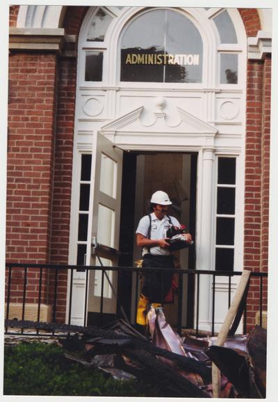 An unidentified man is carrying materials out of the Administration Building after the fire was put out