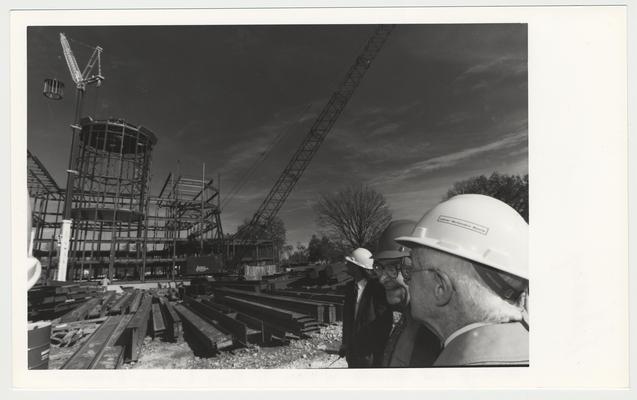 William T. Young in white construction hat and other men are watching the construction of the William T. Young Library