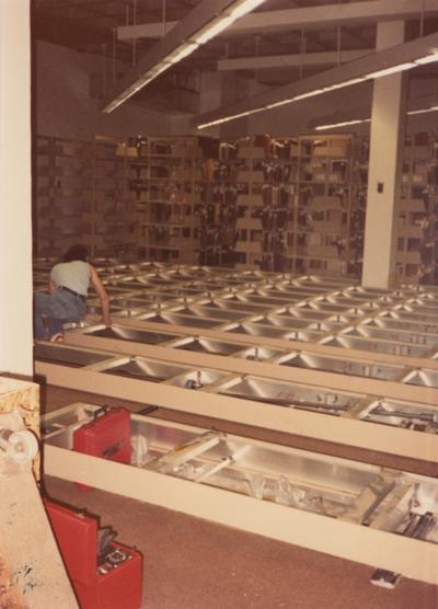 A color photo of an unidentified person building shelves for periodicals and serials on the second floor of Margaret I. King North Library. Photographer: Terry Warth