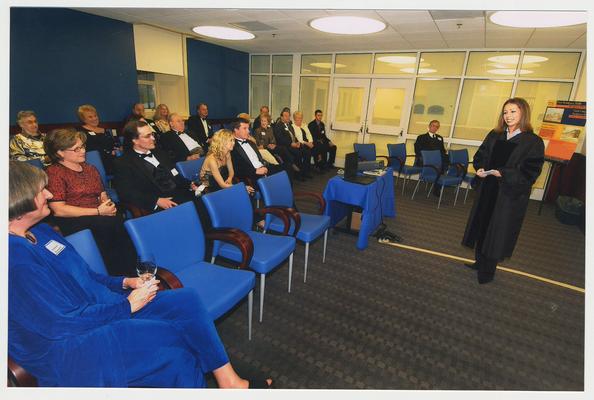 A UK student is telling the history of UK.  Jeannine Blackwell (Dean of the Graduate School) is on the far left.  They are at a ceremony for the reopening of the Main Building