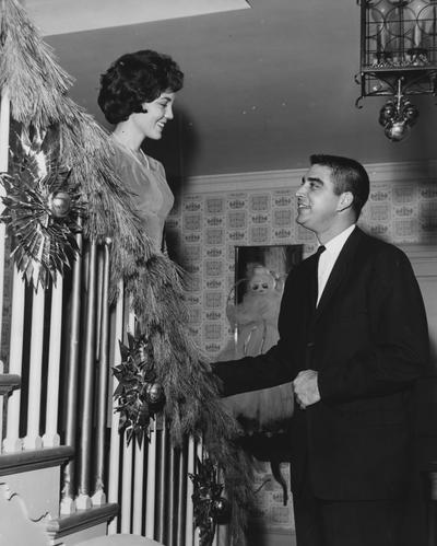 Nancy Clay McClure looking at a man as she comes down the stairs of Kappa Alpha Theta sorority during the winter of 1962. This picture appears second on page 43 in the 1962 