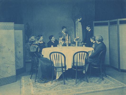 Four unidentified women and four unidentified men sitting around a table