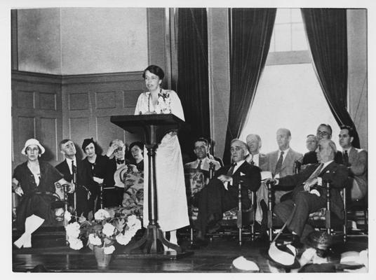 Eleanor Roosevelt addresses an audience in Memorial Hall; Seated behind her are Mrs. Morgenthau (spouse of Secretary of the Treasury, University President Frank L. McVey, and Governor Ruby Laffoon