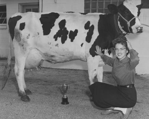 Woman kneeling beside a trophy-winning cow