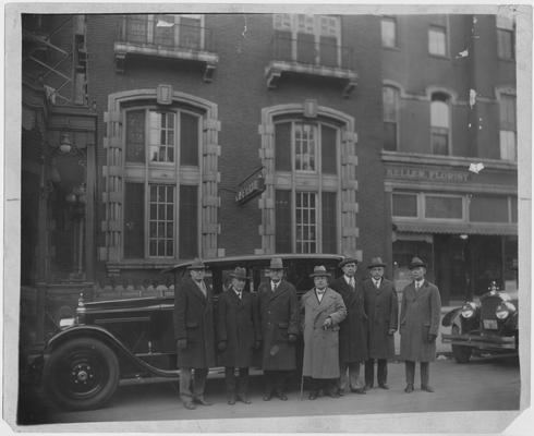 Dean F. Paul Anderson, fourth from the left with a walking stick with unidentified men in downtown Lexington.  Keller Florist is in the background