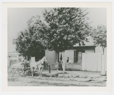 Charlie McCarthy [curbside in wagon] with family in background in front of family home