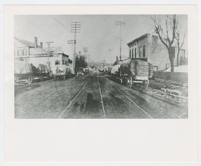 Horse drawn wagons carting tobacco on sticks on South Broadway, just below the railroad tracks