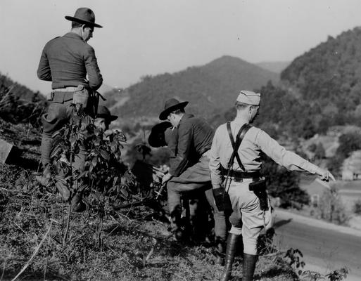 National Guardsmen on a hillside, overlooking a road