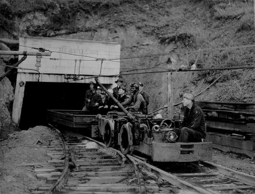 Miners on a mining cart leaving a mine entrance