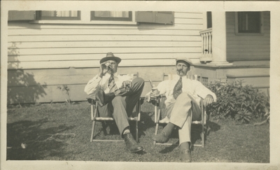 Two men in yard; drinking, smoking, and sitting in lawn chairs