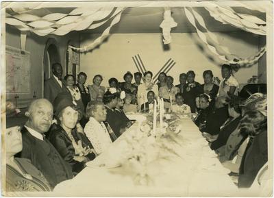 Group of African Americans sitting at a table including William Henry Fouse (1868-1944), Elizabeth Beatrice Cooke Fouse (1875-1952), Pastor of East Second Street Christian Church of Lexington, Kentucky Elder R.L. Saunders, and Emma W. Saunders