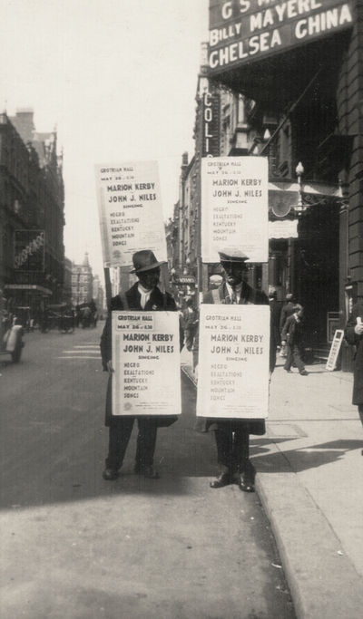 Sandwich-board man advertising a concert by John Jacob Niles and Marion Kerby; London, England