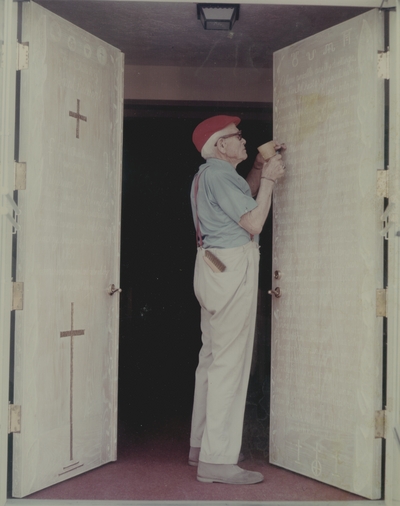 John Jacob Niles puts the finishing touches on carving of doors for St. Hubert's Church; Lexington Herald-Leader