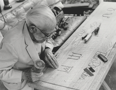 John Jacob Niles carving wooden plaque; Helm Roberts