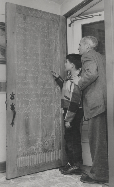 John Jacob Niles with son Tom in front of carved door at Boot Hill Farm