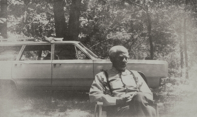 John Jacob Niles sitting in front of station wagon