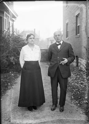 a man and woman standing together in between 2 buildings