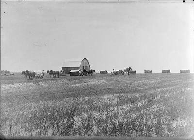 a farm with a barn, horses, and other buildings off in the distance