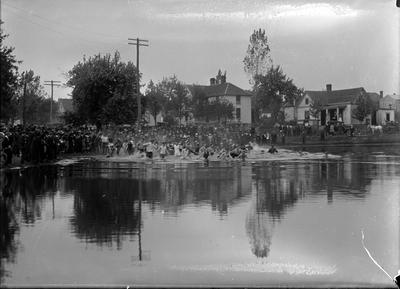 people standing around a lake, others are in the lake