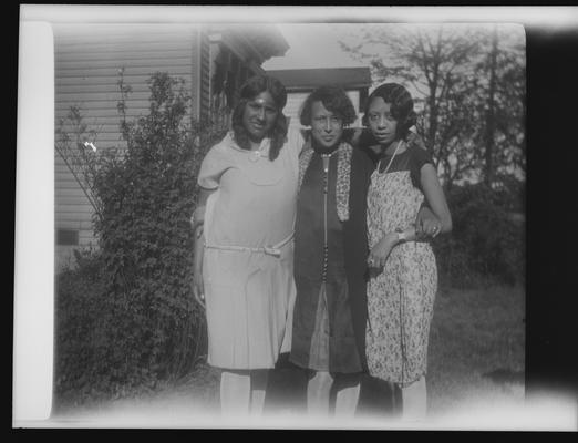 Negative of three unidentified women in a garden