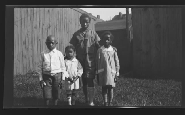 Negative of four children in a yard