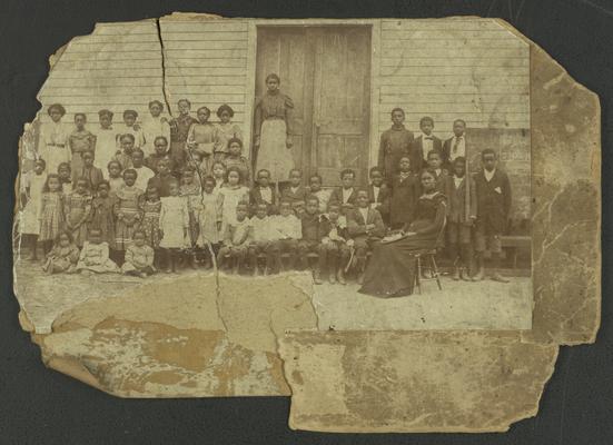 Portrait of unidentified black school pupils and teachers in front of school building