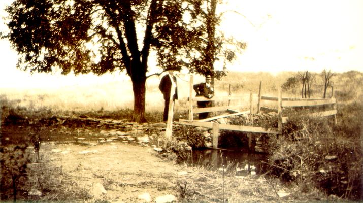 Two men on a small bridge over a creek