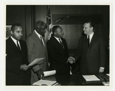 Dr. Martin Luther King, Jr., shaking hands with Kentucky Governor Edward T. Breathitt, Jackie Robinson to King's left, Frank Stanley Jr. to his extreme left