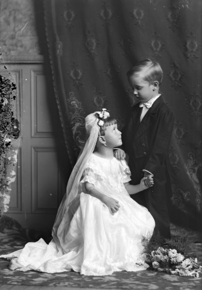 Portrait of a boy and girl with the girl bending down on one knee identified as 