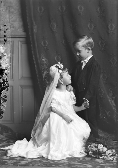 Portrait of a boy and girl with the girl bending down on one knee identified as 