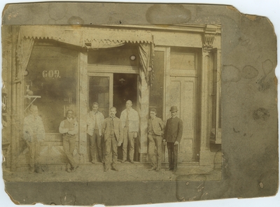 Seven unidentified African American males standing in front of an unidentified building