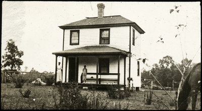 Unidentified African American woman and boy standing in front of a large white house