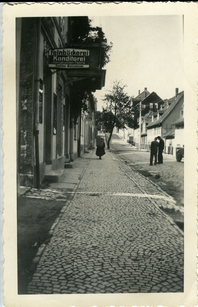 Street with three people.  Sign says Feinbackerei Konditorei  