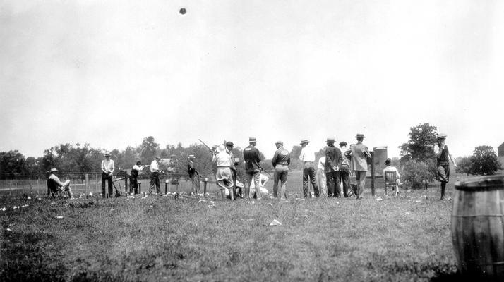 Group of men at a fish fry and shoot, some aiming guns